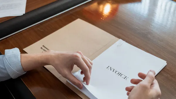 Manos ordenando facturas y comprobantes sobre un escritorio de oficina