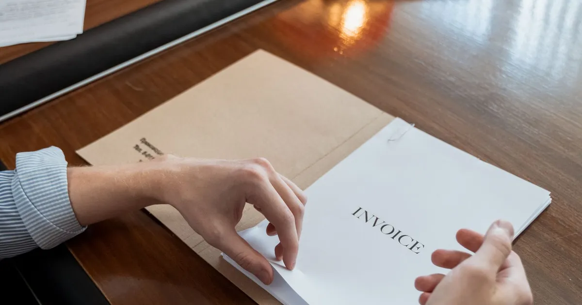 Manos ordenando facturas y comprobantes sobre un escritorio de oficina
