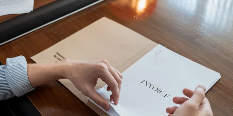 Manos ordenando facturas y comprobantes sobre un escritorio de oficina