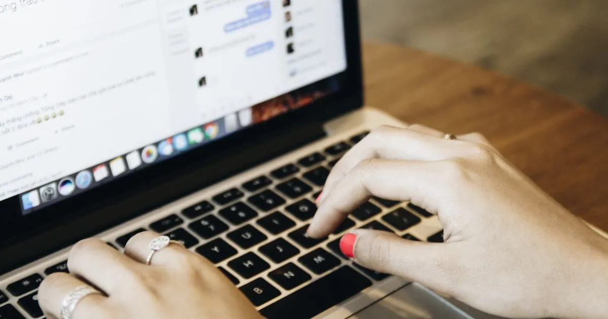 Manos escribiendo en una laptop con una aplicación de mensajería abierta