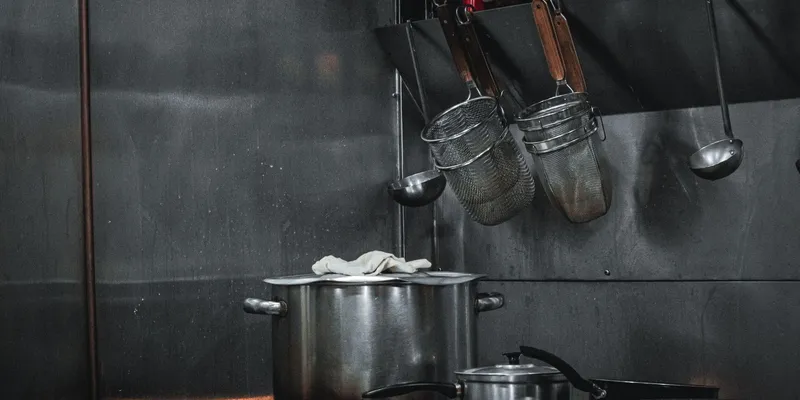 Cocina industrial de acero inoxidable con ollas y utensilios colgados
