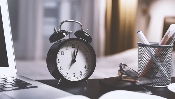 Reloj despertador junto a una laptop en un escritorio de oficina