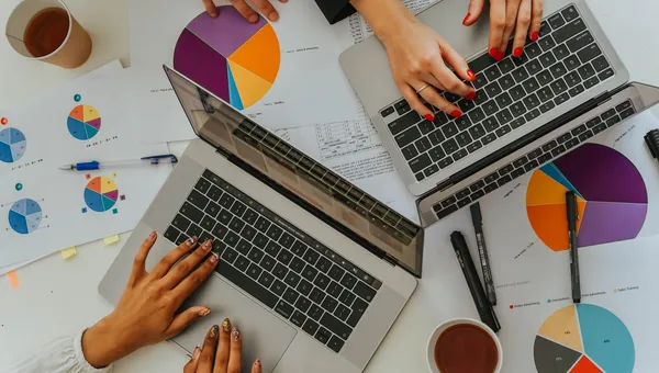 Equipo analizando gráficas con laptops en una reunión, vista desde arriba