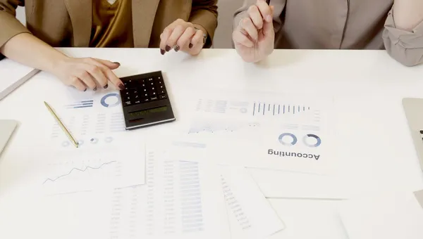 Dos personas revisando cifras y documentos contables sobre una mesa